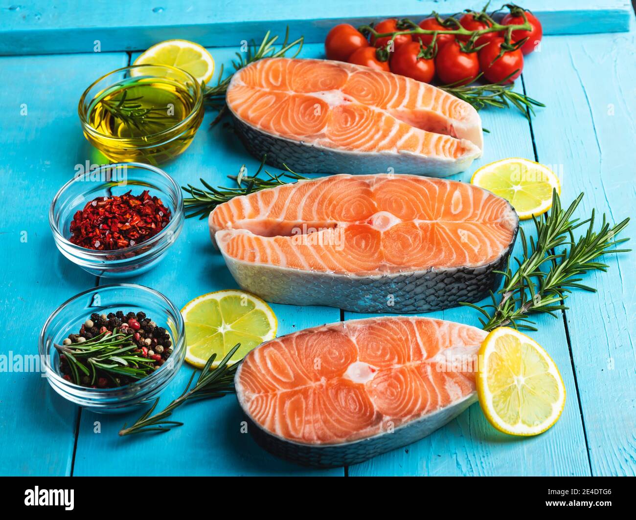 three raw fresh steak fish trout, salmon and spices on a blue wooden background Stock Photo