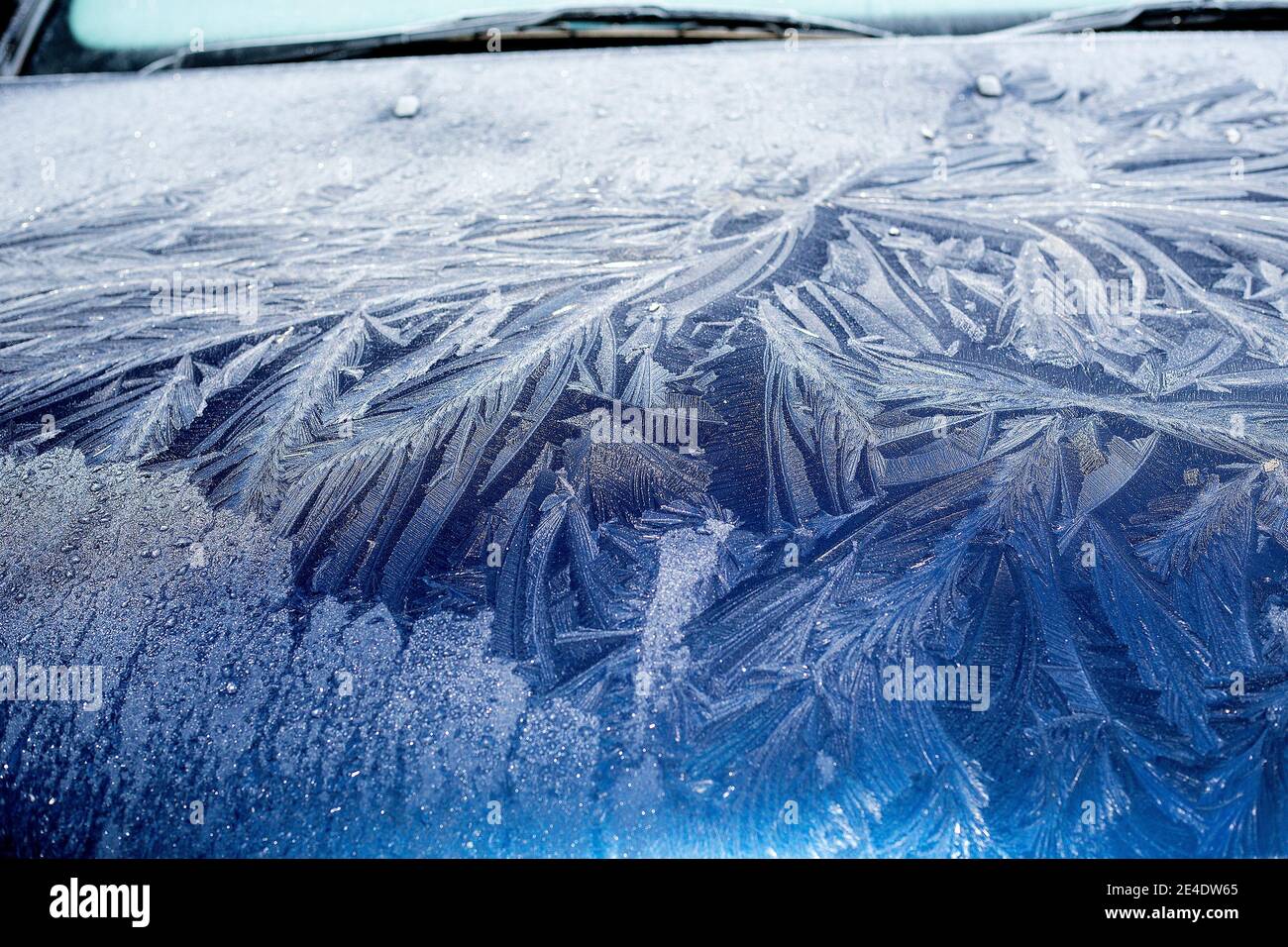 A thick, patterned, frost on the windscreen and bonnet (hood) of a blue Ford Mondeo car. Stock Photo