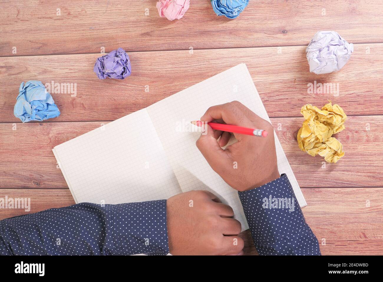 crumpled paper ball and notepad on wooden table. Stock Photo