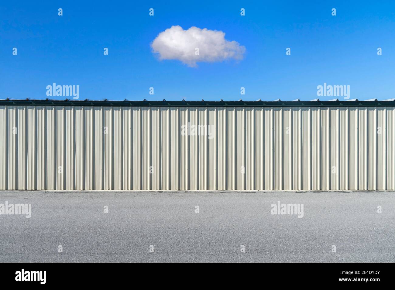 Simple minimalistic corrugated metal exterior wall with single cloud in sky. Stock Photo