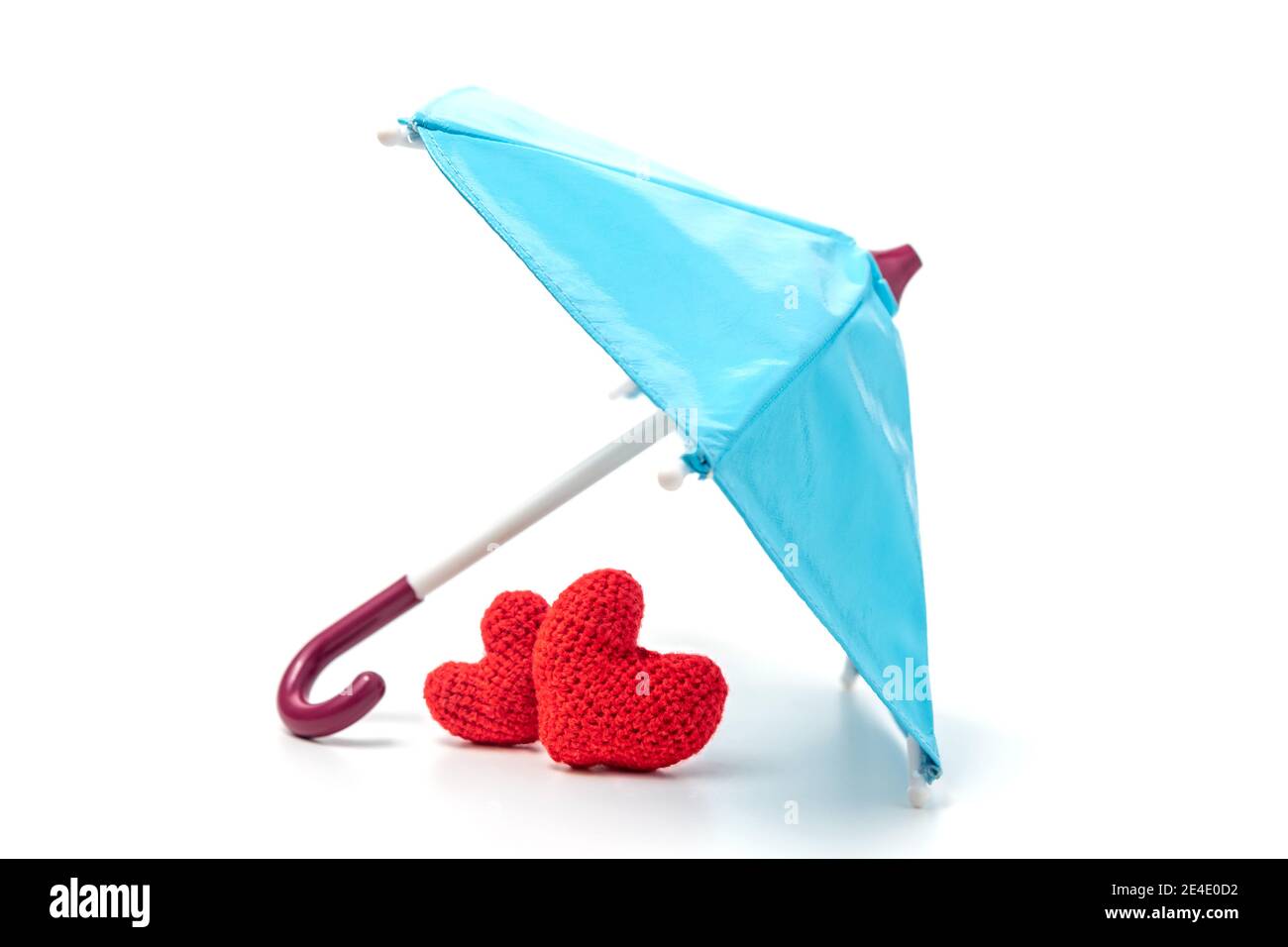 Pair of knitted red hearts under an umbrella. Life or health insurance, love. The concept of importance of family and home Stock Photo