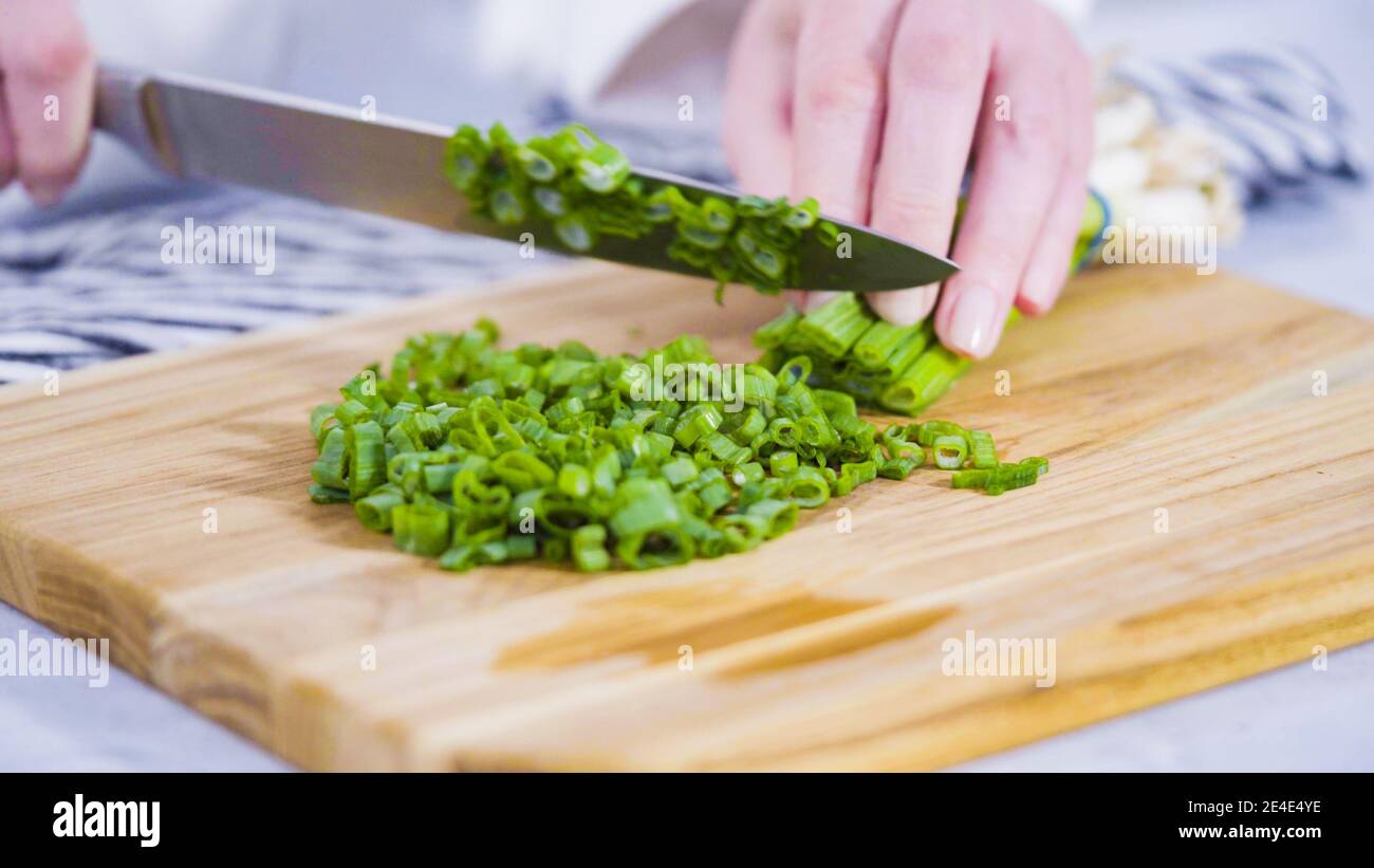 Step by step. Chopping organic green onions on a wood cutting board ...