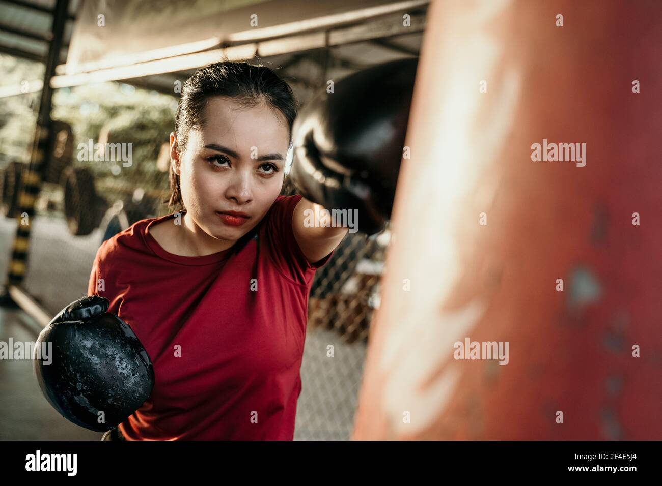 woman boxer fighter doing exercise hitting punching bag with copyspace at boxing camp Stock Photo