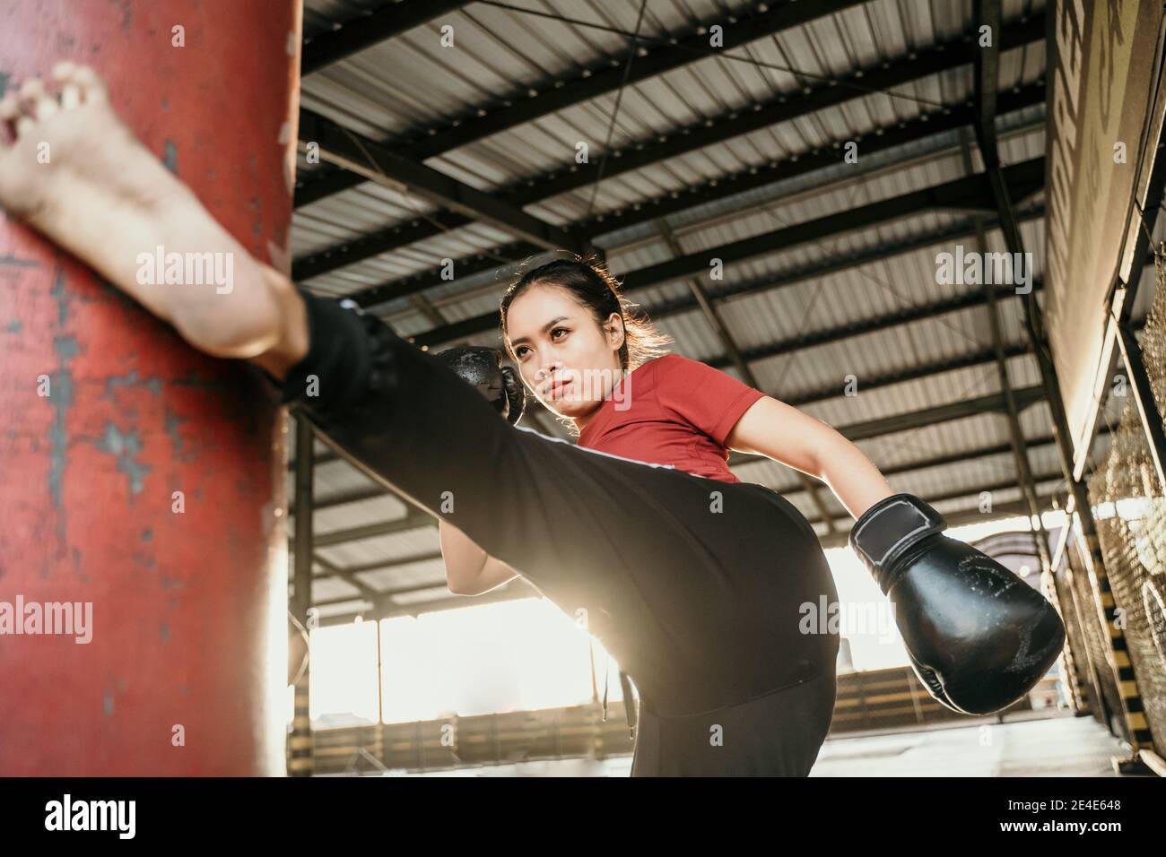 The young woman workout a kick on the punching bag in gym Stock Photo