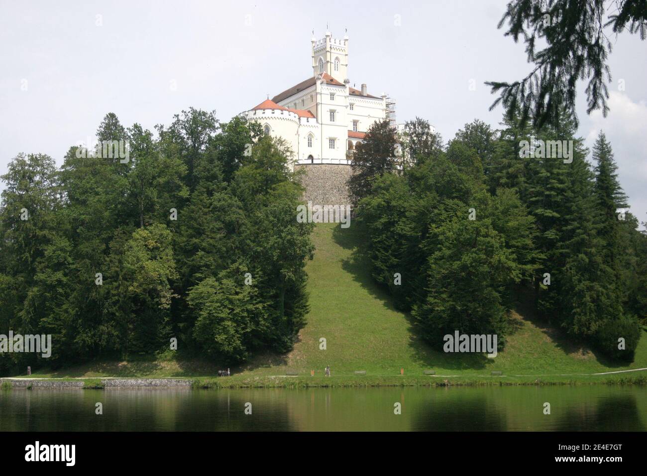 A medieval castle surrounded by forest and a lake Stock Photo