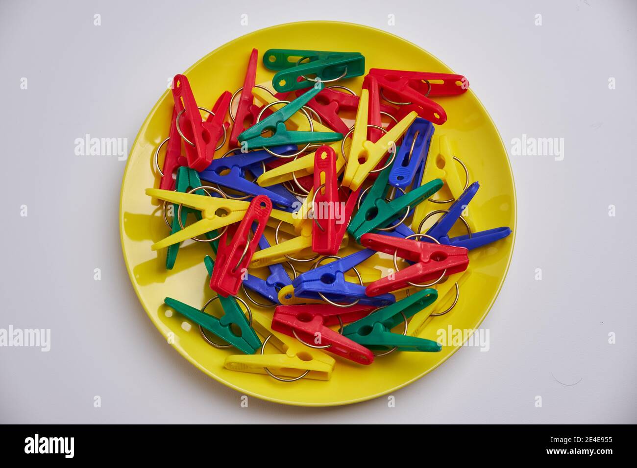 Multicolor laundry clips on yellow plate Stock Photo