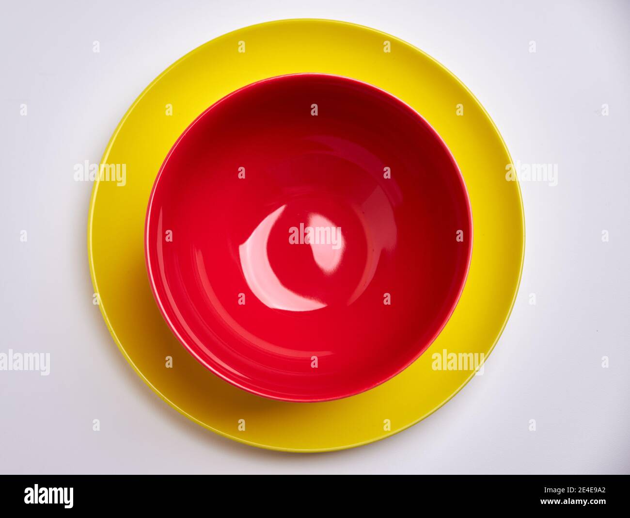 Empty red bowl on yellow plate with white background Stock Photo