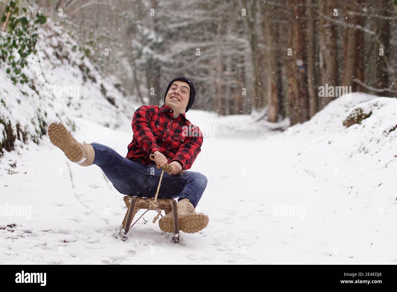Man fooling around on a sleigh and making a crazy face - having fun on the sledge Stock Photo