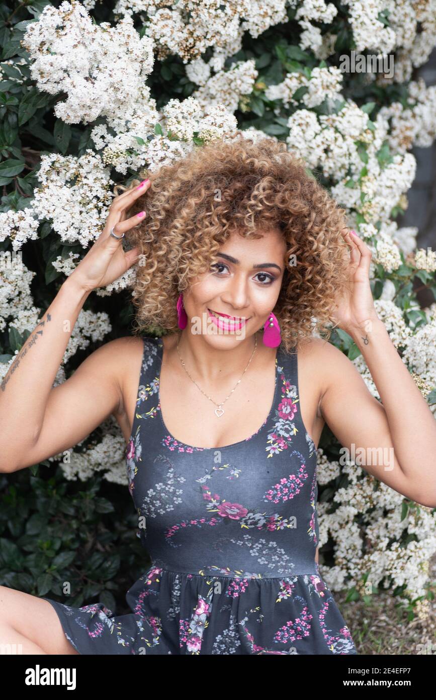 Vertical shot of a Hispanic female with curry hair posing on flower ...