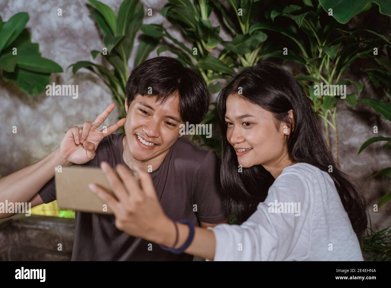 Happy young couple in love having fun and taking selfie portrait on outdoor cafe at night Stock Photo