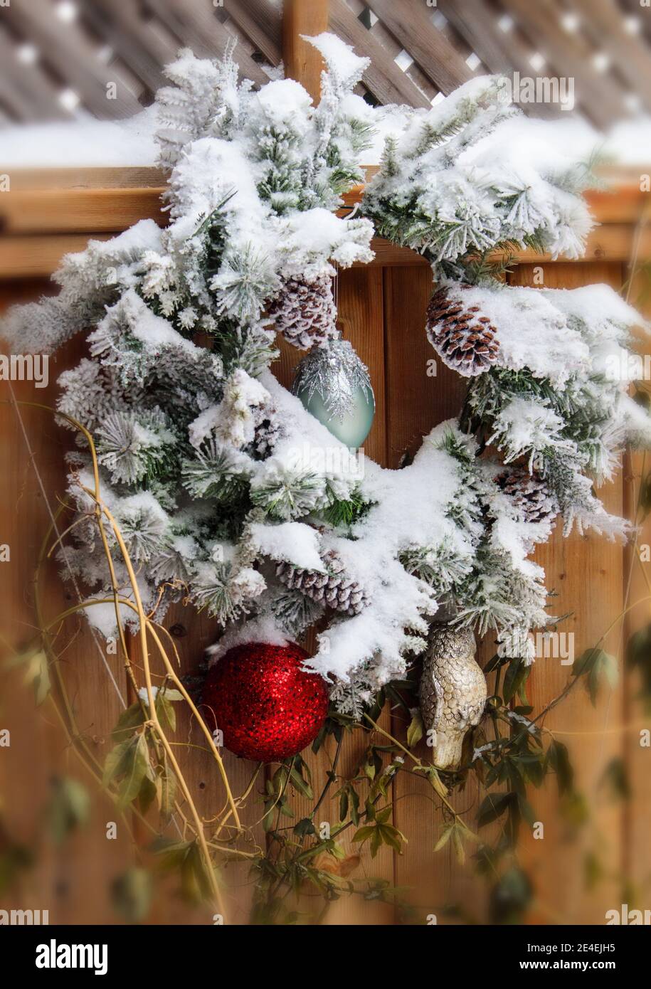 A Christmas wreath hanging on the wooden fence during Winter Celebrations. Stock Photo