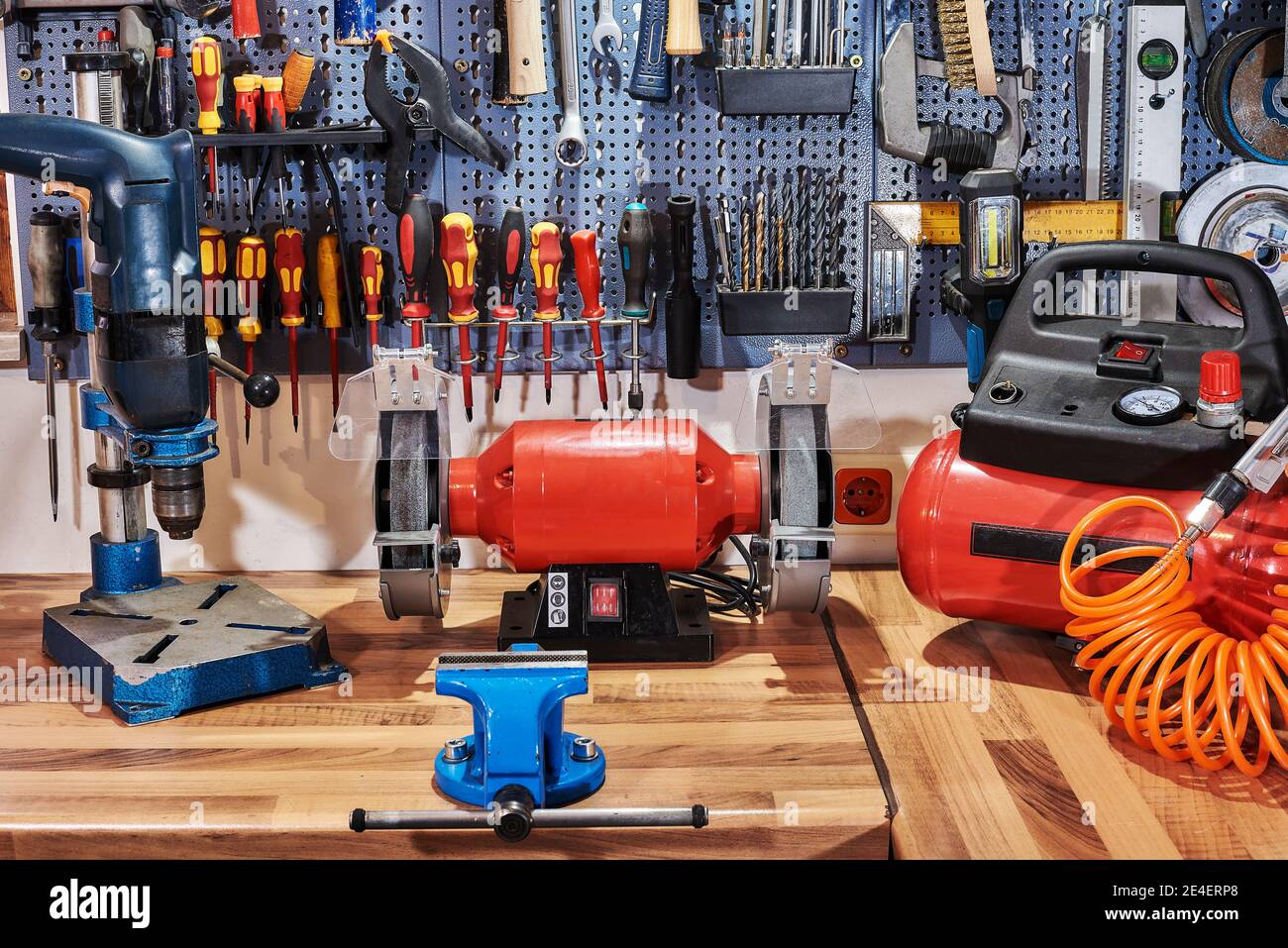 A collection of assorted tools hanging on the wall with a work bench Stock Photo