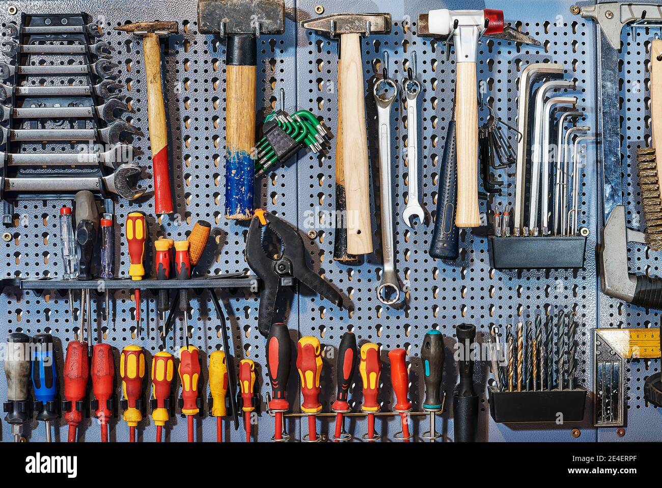 A collection of assorted tools hanging on the wall with a work bench Stock Photo