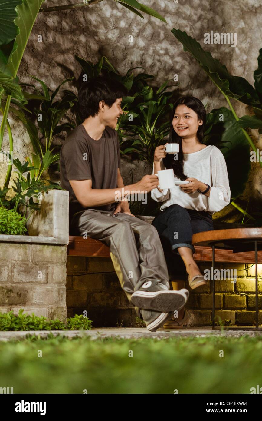 romantic dating of teenage couple chatting and enjoy a coffee in the garden of the house Stock Photo