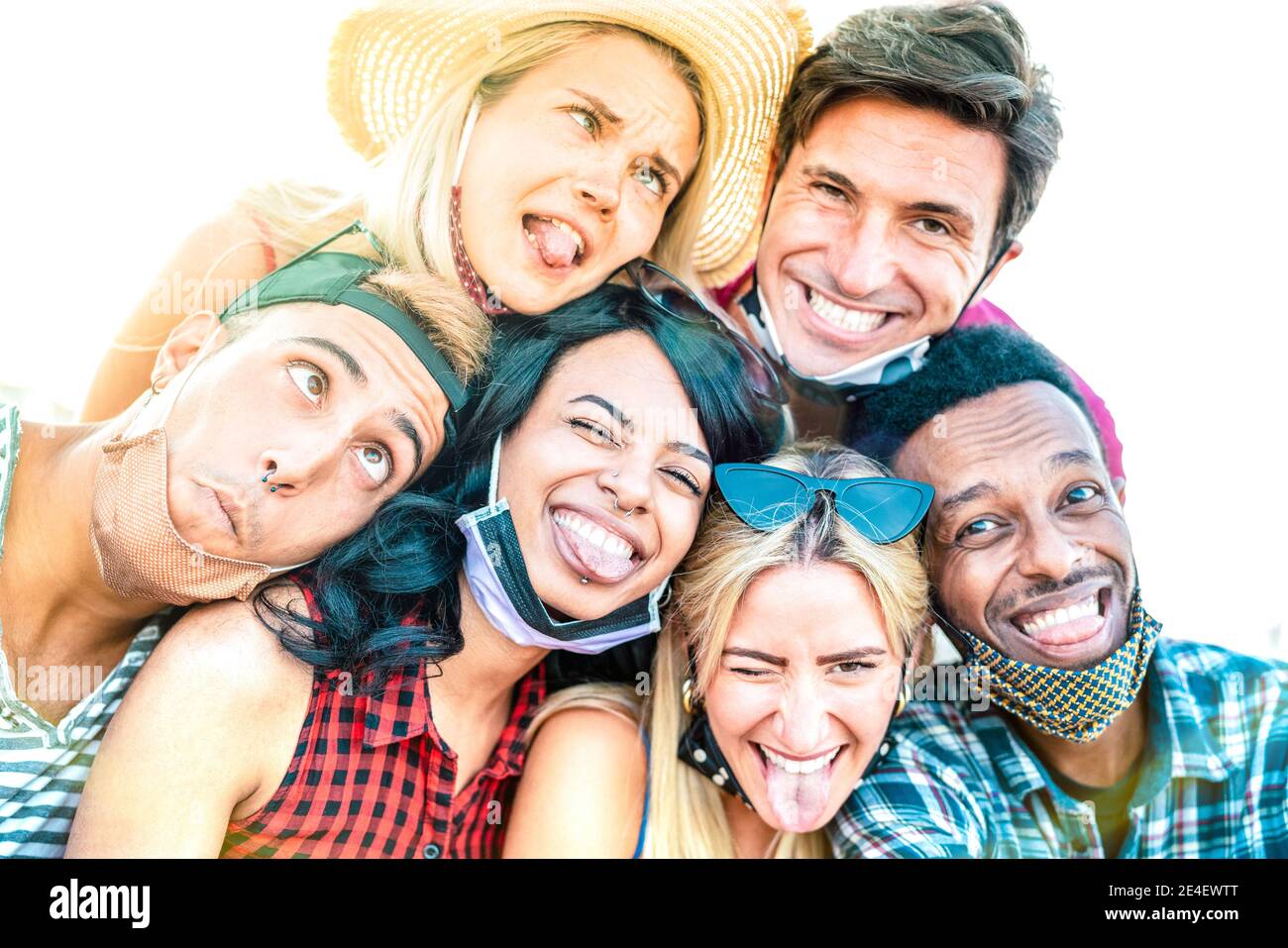 Multiracial friends taking crazy selfie with open face masks - New normal friendship concept with young people having fun together Stock Photo