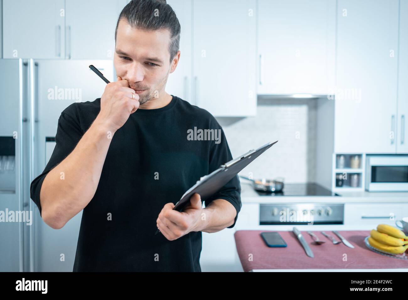 fitness nutritionist man count calories with clipboard at modern kitchen concept Stock Photo