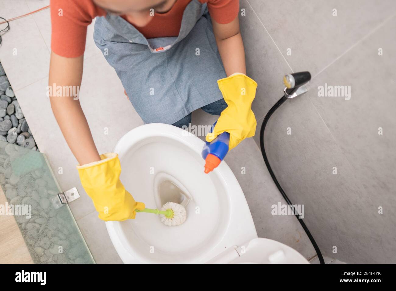 someone wearing gloves clean the toilet with a brush and porcelain