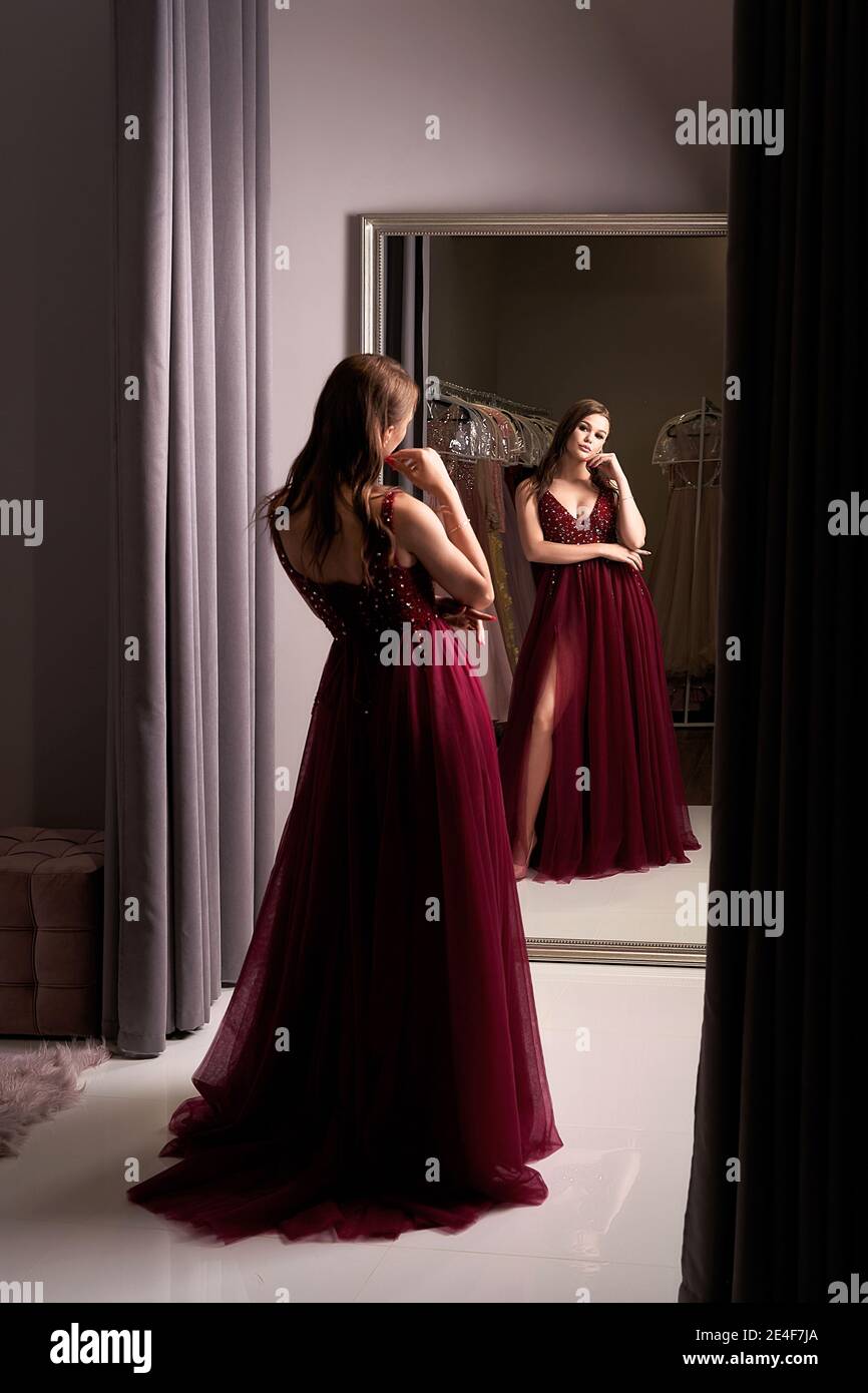 Young beautiful wearing a full-length dark crimson red chiffon prom ball gown decorated with sparkles and sequins. Model in front of Stock Photo - Alamy