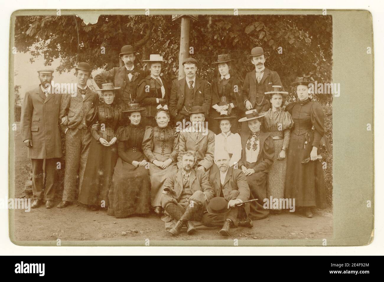 Original Victorian cabinet card full of characters and fashions. Here is John Baxter seated in the centre probably with his wife on the left dressed in her finest, surrounded by a group of his factory workers, dressed in their 'Sunday Best' clothes, perhaps on a company outing or country walk, circa 1897, U.K Stock Photo