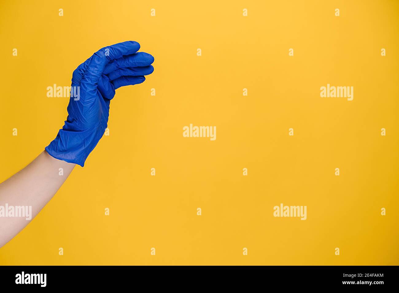 Close up of young woman bending hand fingers fast, wears medical protective gloves, isolated on yellow studio background with copy space Stock Photo