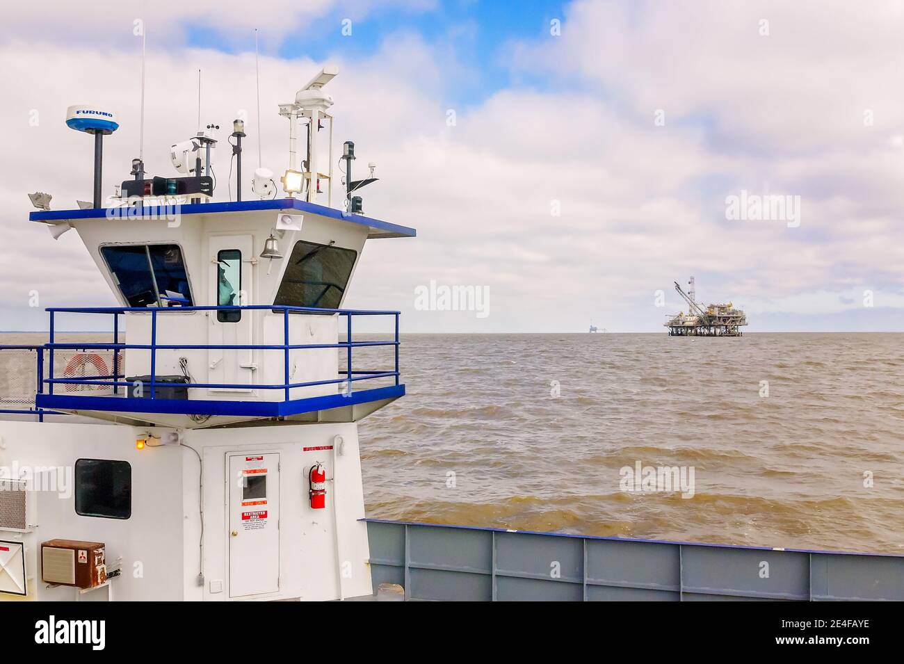 The Mobile Bay Ferry passes a natural gas rig, March 4, 2016, in Dauphin Island, Alabama. HMS Global Maritime operates as many as two ferries daily. Stock Photo