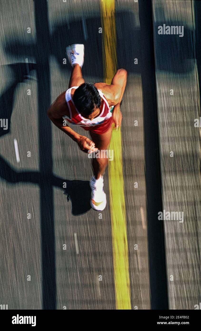 Blurred motion image of  legs and feet of a runner, in a marathon -  high viewpoint. Stock Photo