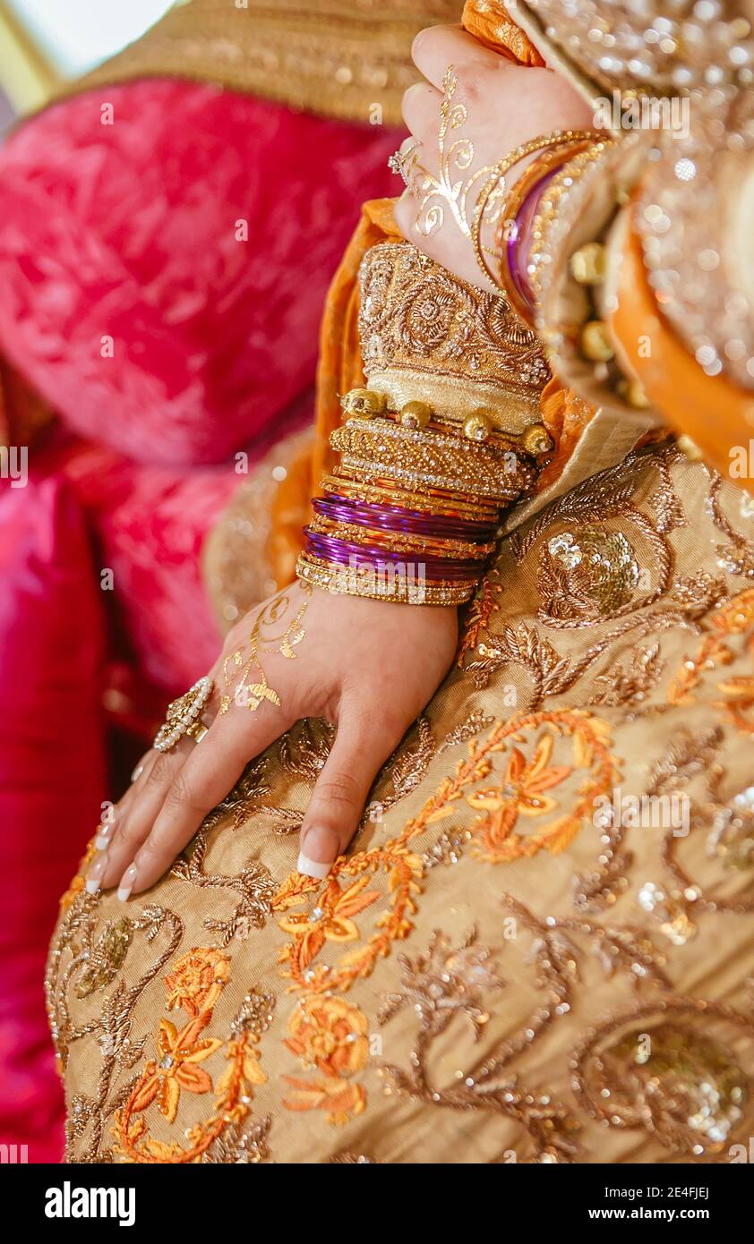 Close up indian pakistani bride hands decorated by golden henna, jewelry  bracelets and rings at mehndi sangeet party at home interior with velvet  pink Stock Photo - Alamy