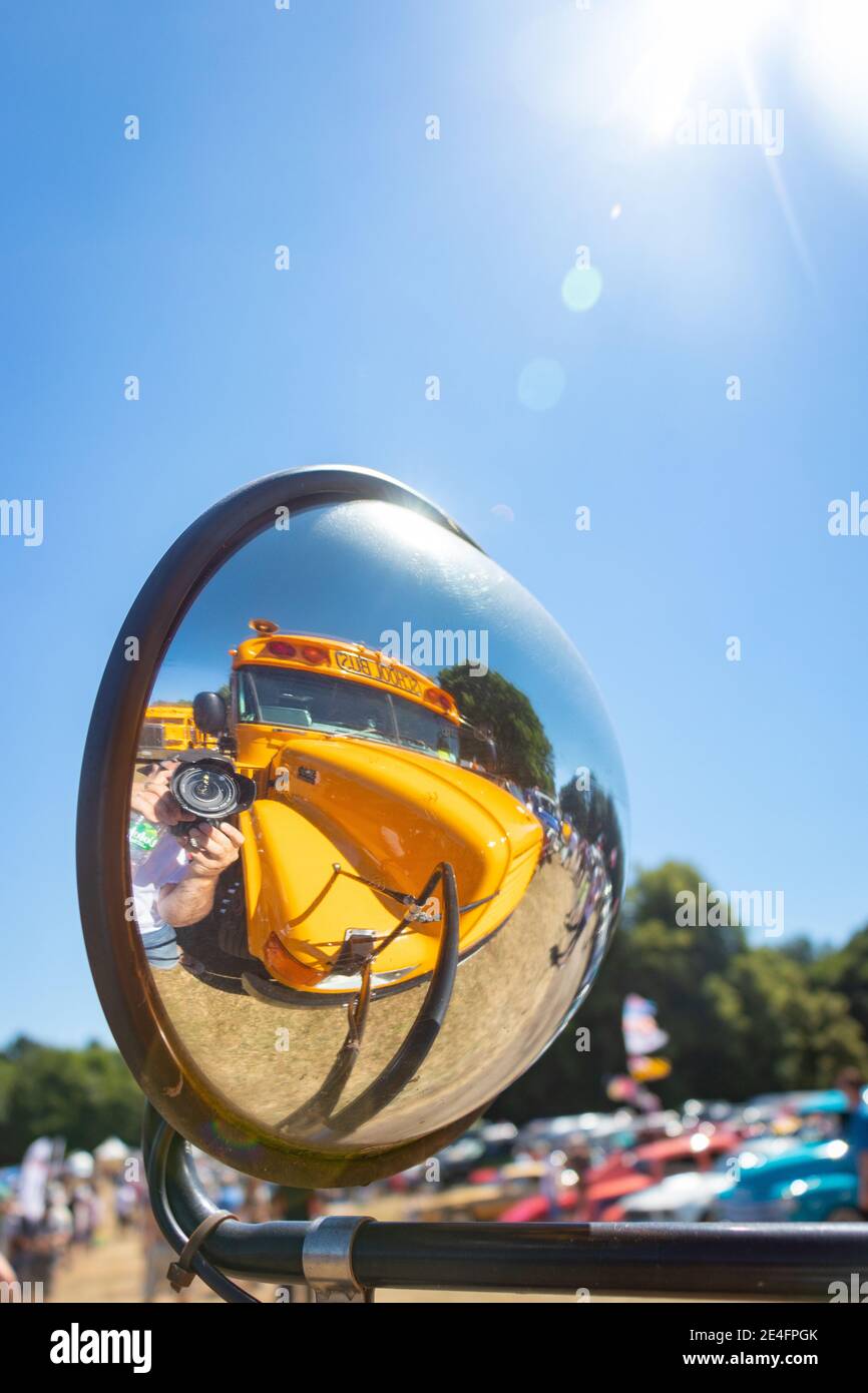 reflection in convex wing mirror fender of yellow American school bus