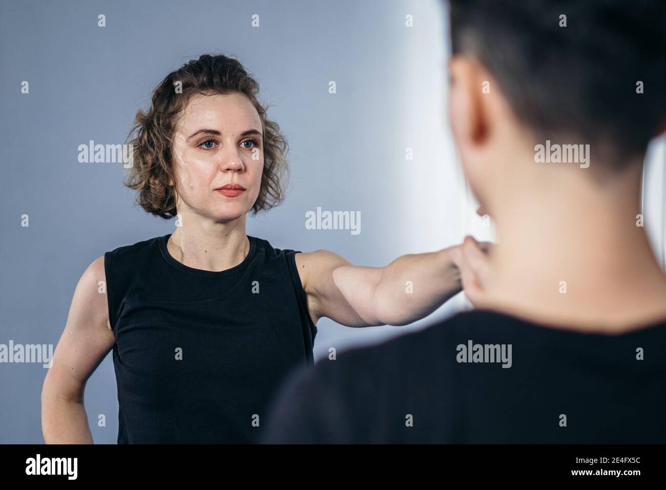 Coach teaches athlete to hit kick. Strong female martial arts athletes in their taekwon-do training. Two young women instructor and student practicing Stock Photo