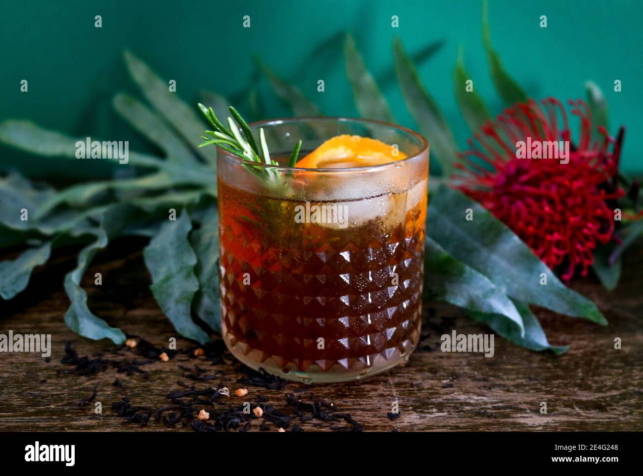 Old fashioned rum or whiskey cocktail in front of a botanical, tropical dark green background Stock Photo