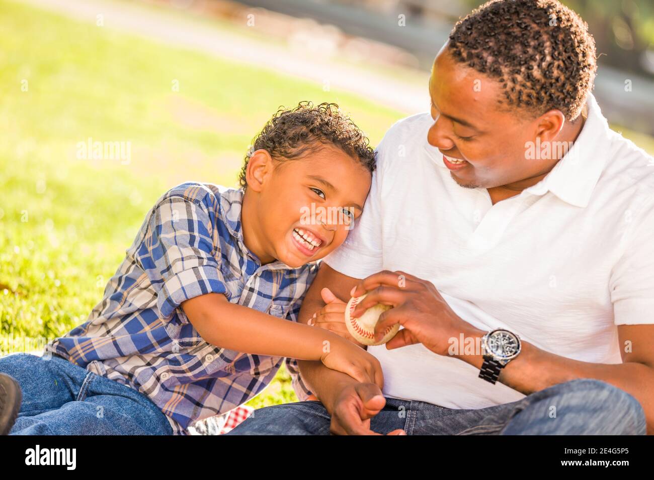 African American Father and Mixed Race Son Playing with Baseball in the ...