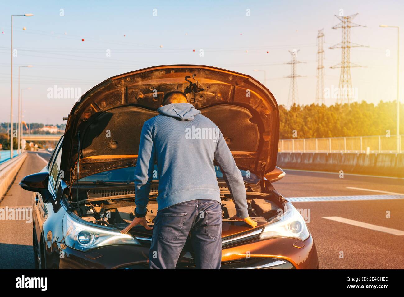 Man with his broken car on the highway roadside. Automobile breaks down on the autobahn. Open the car bonnet, check engine Stock Photo