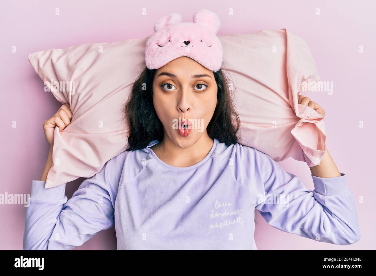 Beautiful middle eastern woman wearing sleep mask and pajama sleeping on pillow afraid and