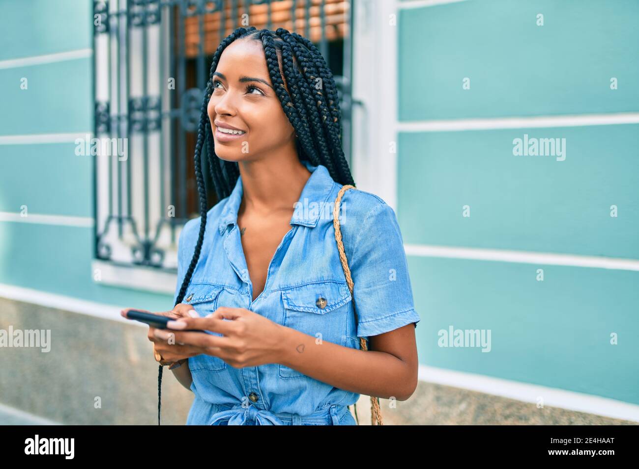 Young african american woman smiling happy using smartphone at the city ...