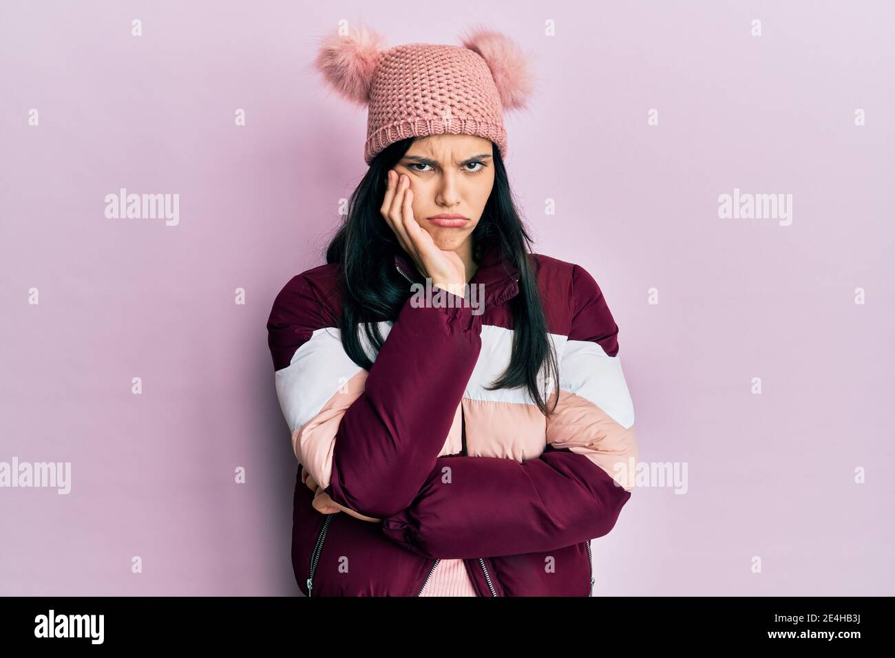 Young hispanic woman wearing wool winter sweater and cap thinking looking tired and bored with depression problems with crossed arms. Stock Photo