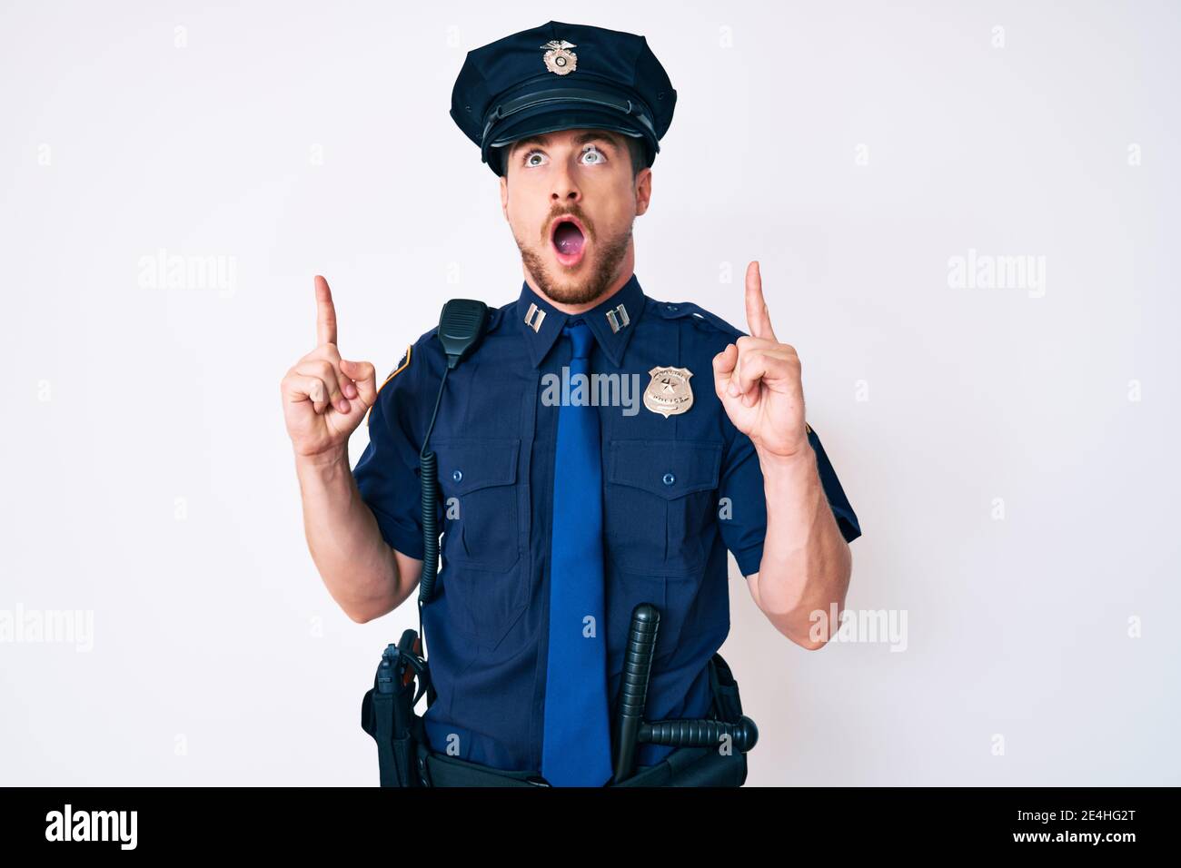 Young caucasian man wearing police uniform amazed and surprised looking ...
