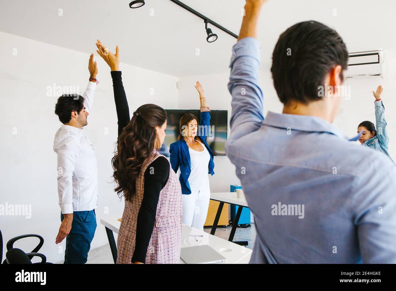 latin business people meditating and doing yoga in office in Mexico city Stock Photo