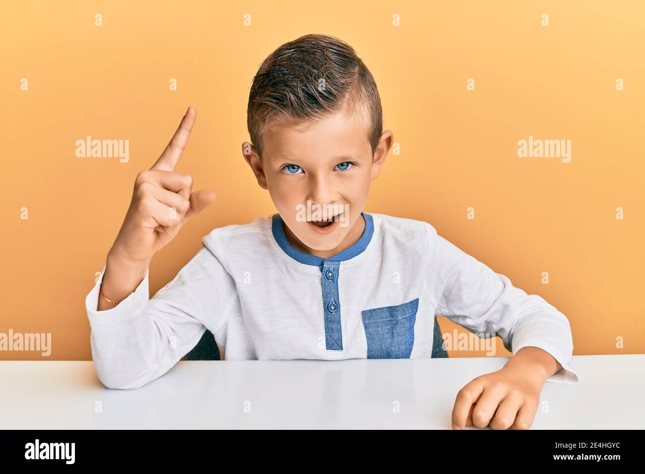Adorable caucasian kid wearing casual clothes sitting on the table ...