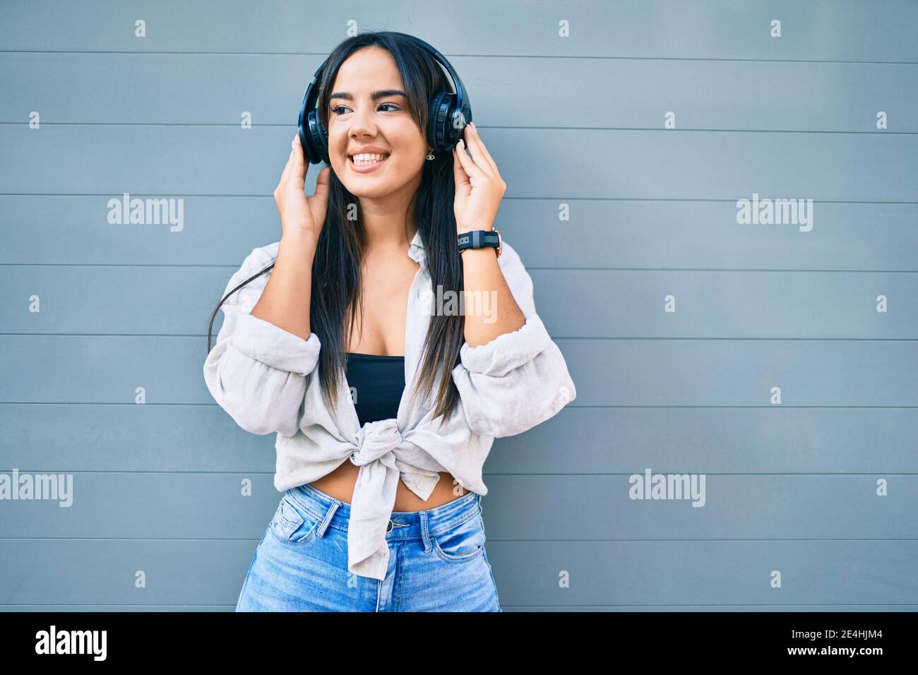 Young hispanic girl smiling happy listening to music using headphones ...
