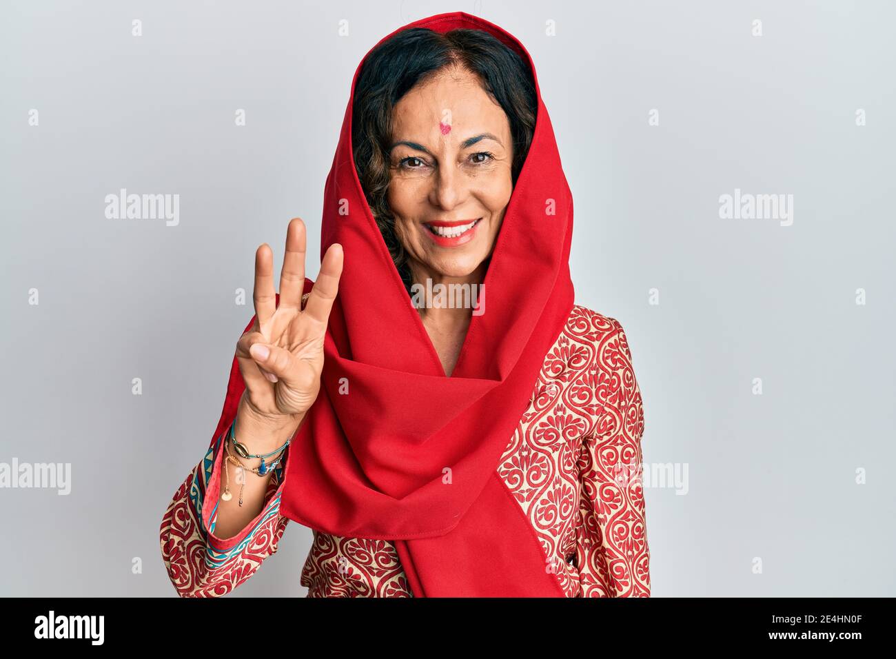 Middle age hispanic woman wearing tradition sherwani saree clothes showing and pointing up with fingers number three while smiling confident and happy Stock Photo