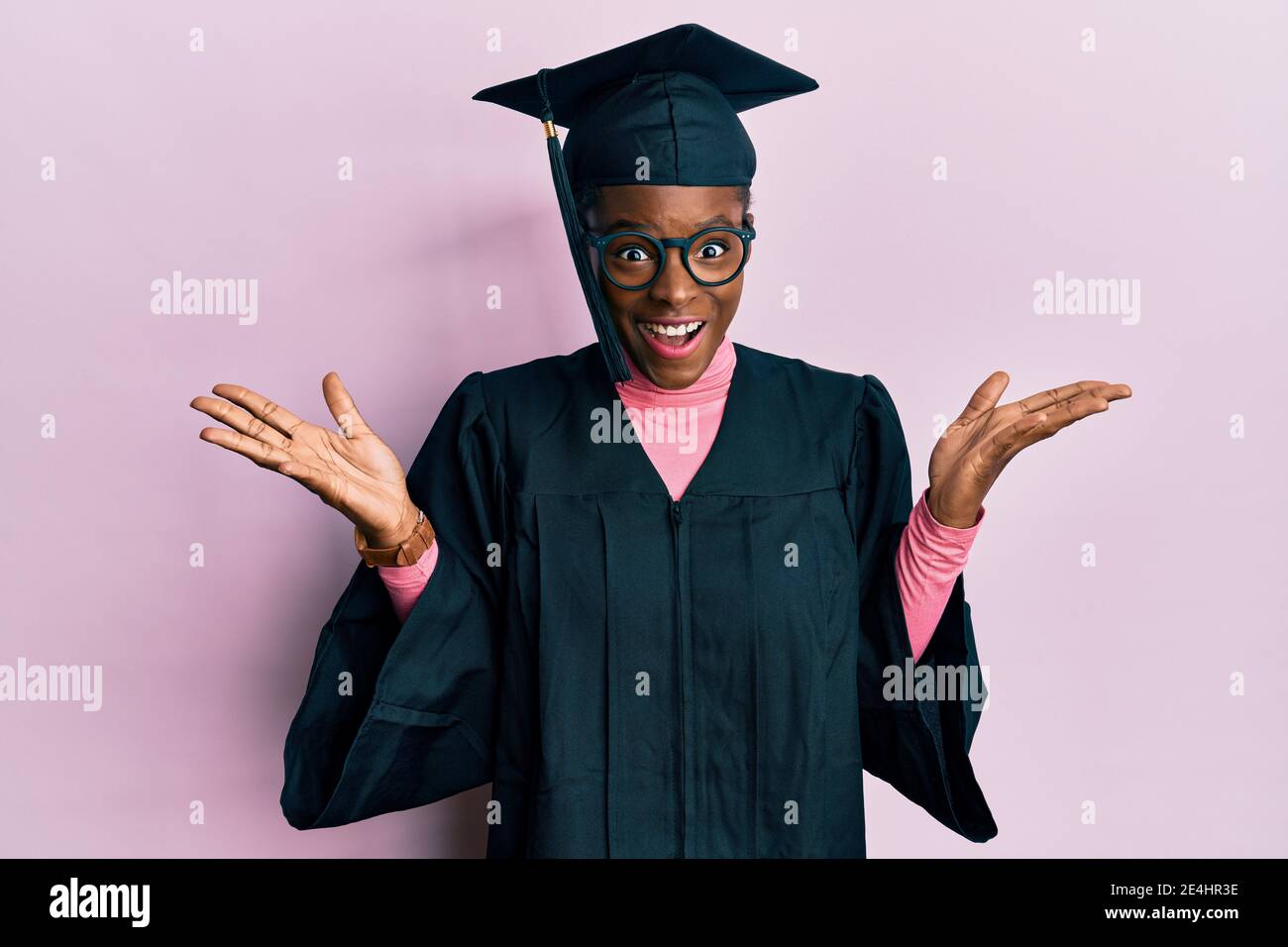 Young african american girl wearing graduation cap and ceremony robe celebrating crazy and amazed for success with arms raised and open eyes screaming Stock Photo