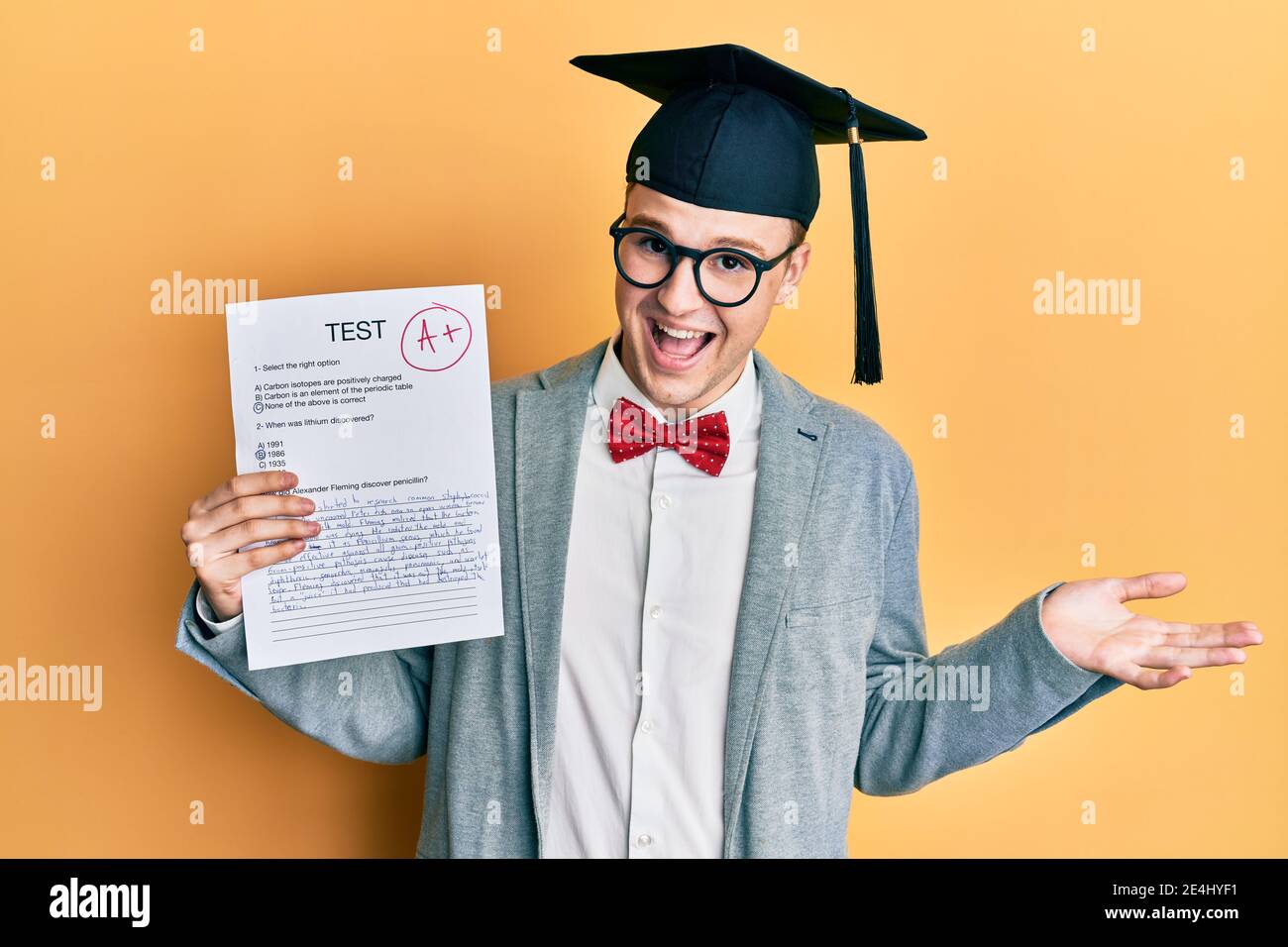 Young caucasian nerd man wearing glasses and graduation cap holding ...