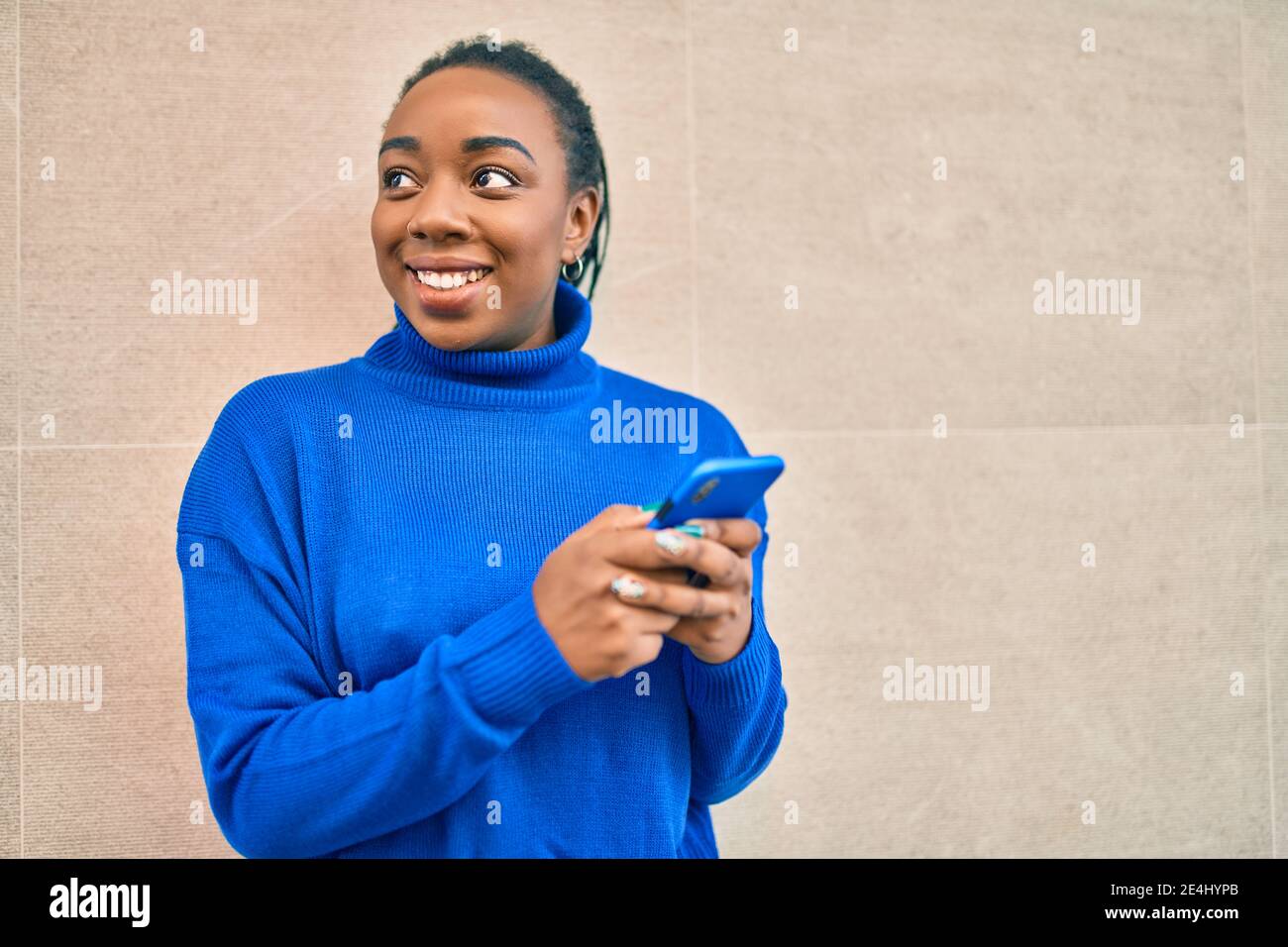 Young african american woman smiling happy using smartphone at the city ...