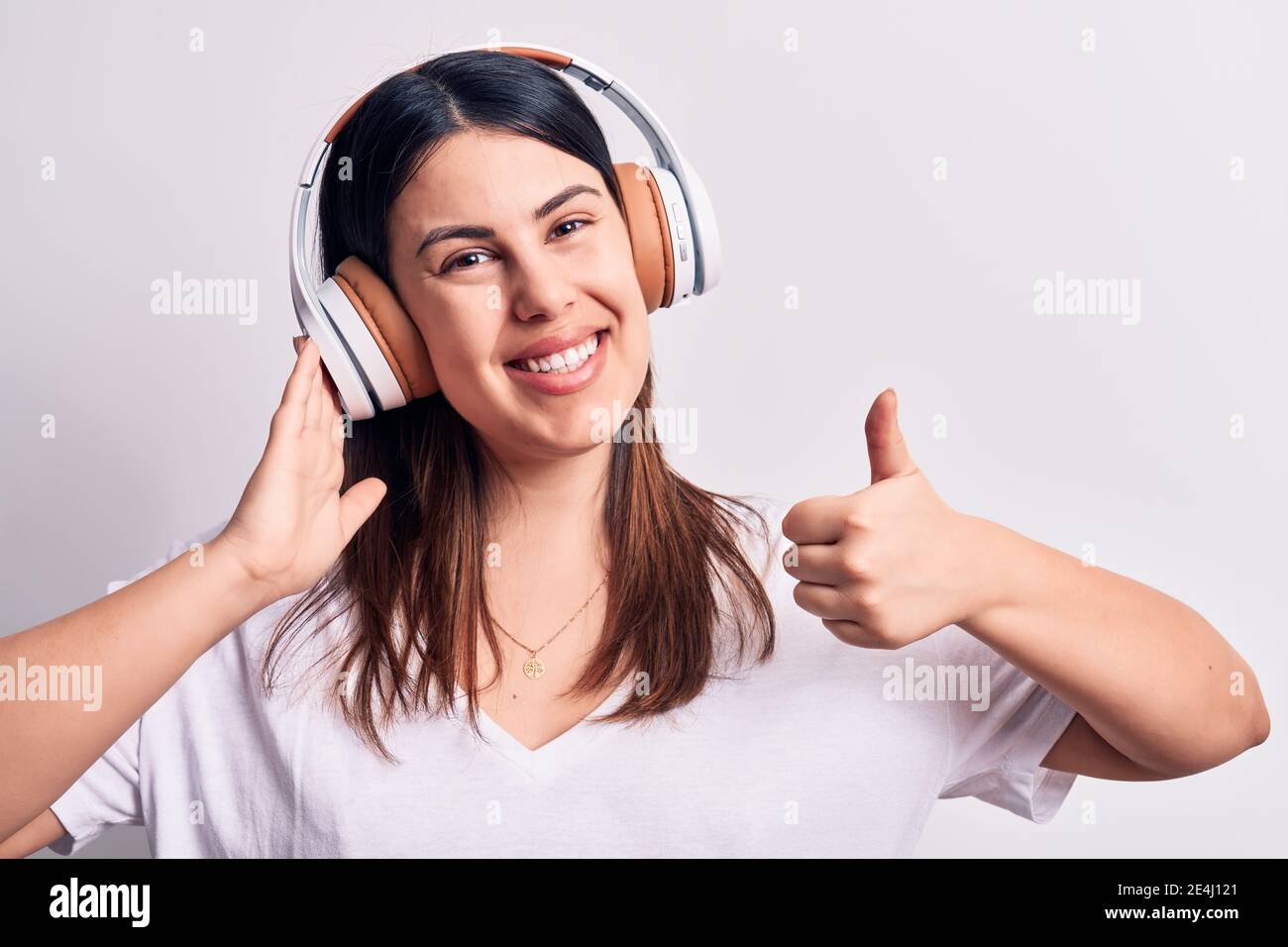 Young beautiful brunette woman listening to music using headphones over ...