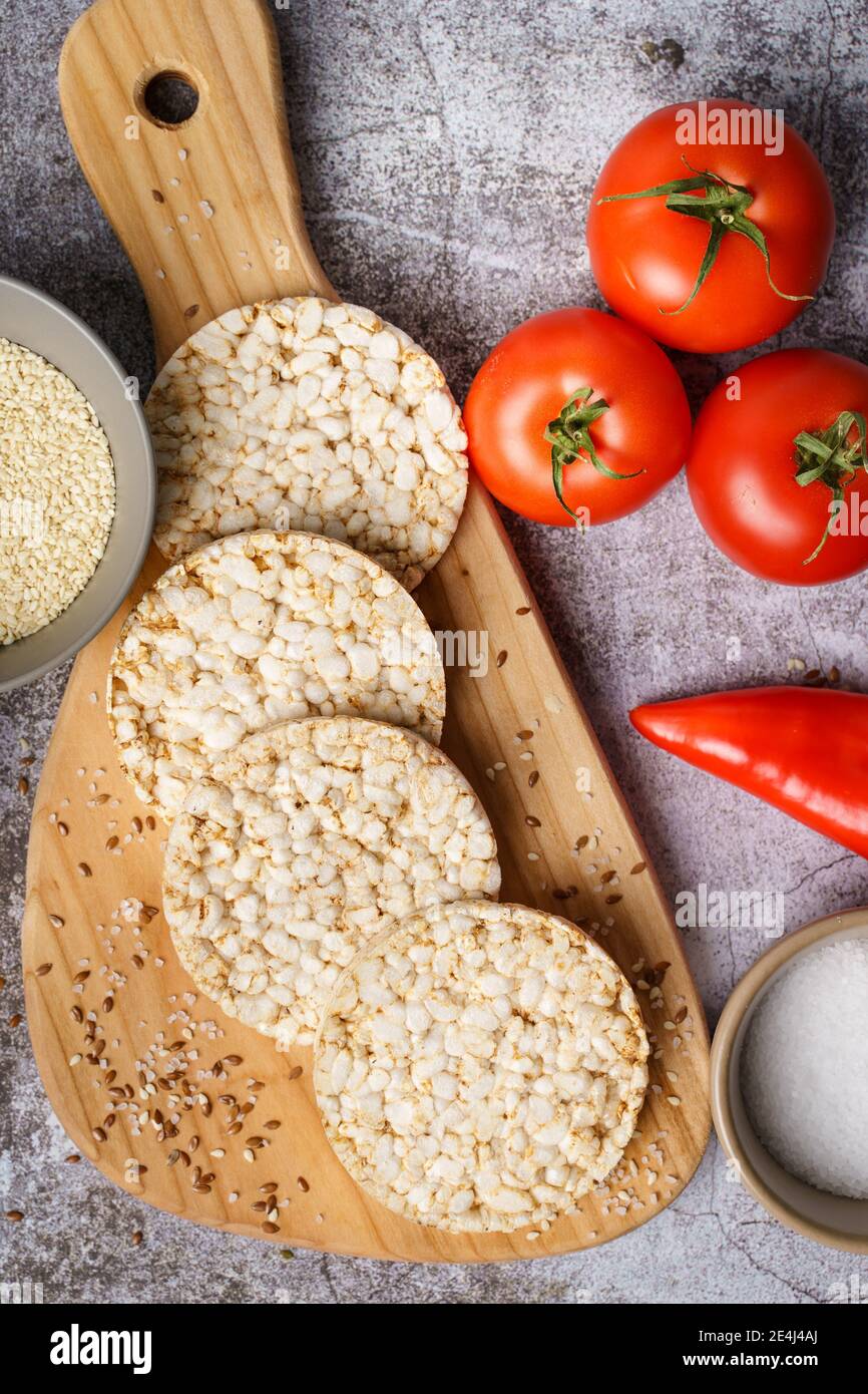 Crispy puffed rice cakes on table hummus spread and tomato vegetables