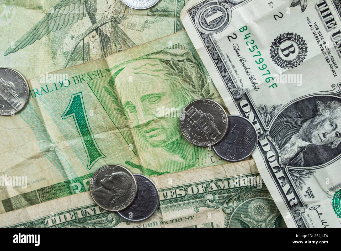 Brazilian currency and U.S. dollar bills stacked together. Stock Photo