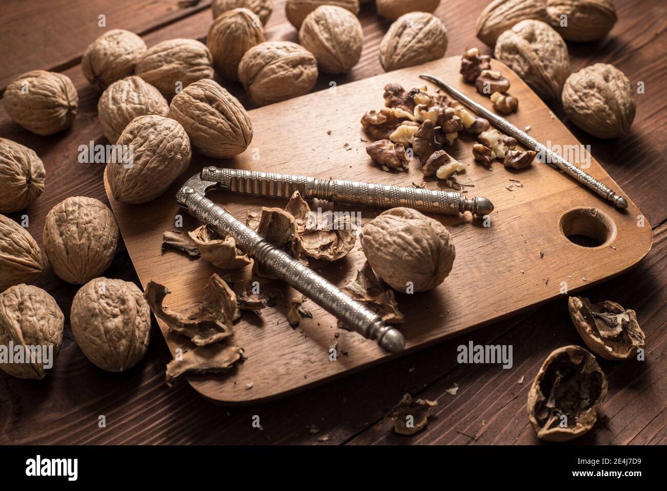 A close up photo of whole walnuts in their shell, broken shells, and