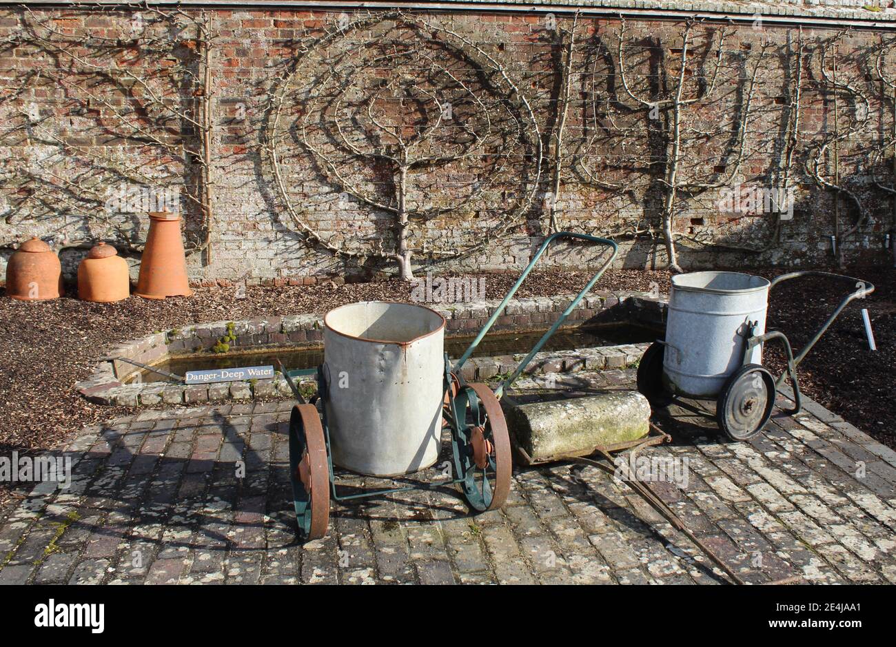 Old antique water carriers in the Victorian vegetable garden at West Dean Gardens, Chichester, West sussex Stock Photo