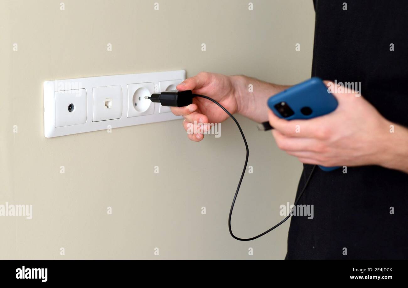 Hand inserting smarthone charger into a socket Stock Photo