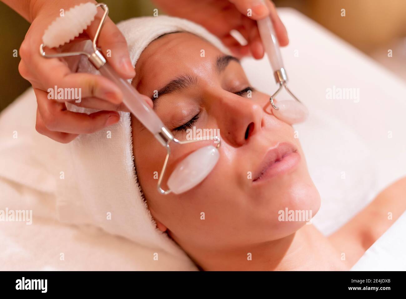 Young female customer receiving facial massage during spa treatment from beautician Stock Photo